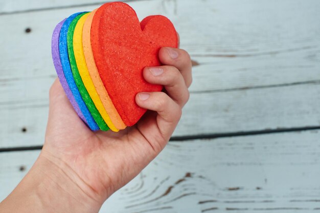 concetto LGBT. Mano su fondo di legno che tiene i colori dell'arcobaleno del cuore