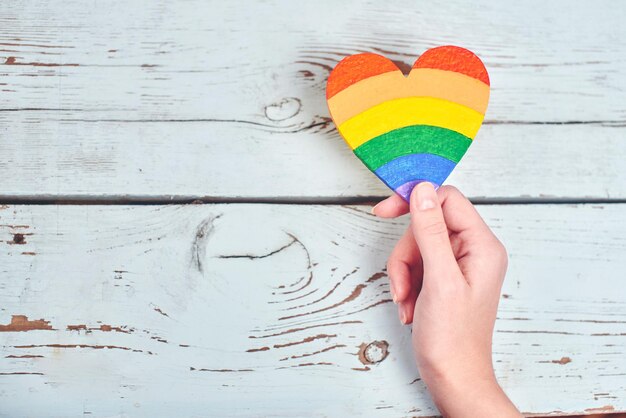 concetto LGBT. Mano su fondo di legno che tiene i colori dell'arcobaleno del cuore