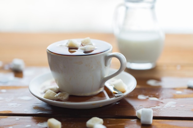 concetto malsano di alimentazione, oggetto e bevande - primo piano di grumo di zucchero annegato in una tazza di caffè su un tavolo di legno