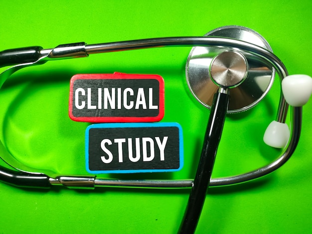 Concetto medico Testo STUDIO CLINICO scritto su tavola di legno colorata con stetoscopio su sfondo verde