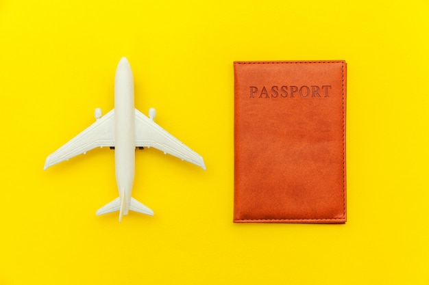 Concetto minimo semplice di viaggio di avventura di viaggio piano di disposizione con aereo e passaporto su fondo moderno d'avanguardia giallo