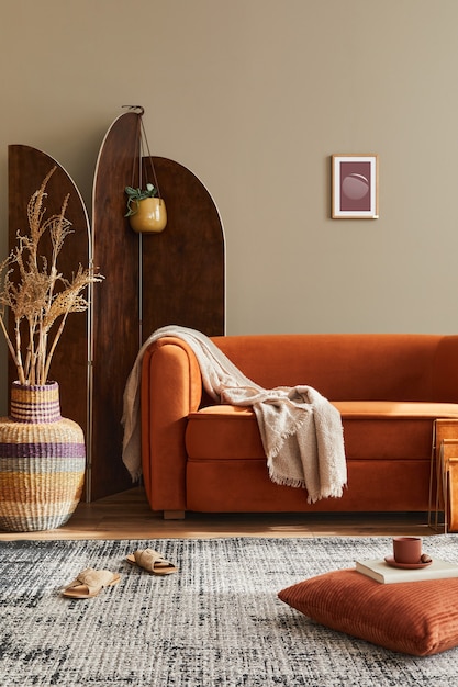 Concetto moderno di interni domestici con divano di design, paravento in legno, cuscino, coperta, cornice, sgabello in legno ed eleganti accessori personali in un elegante arredamento per la casa..