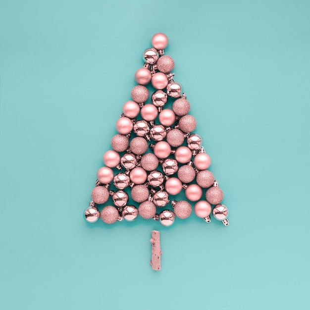 Concetto natalizio creativo Palle rosa per alberi di Natale disposte a forma di albero di Natale su uno sfondo pastello blu