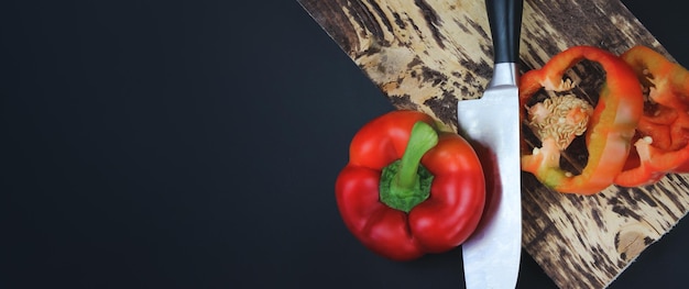 Concetto per un'alimentazione sana Vista dall'alto Copia spazio Dimezzato Pepe succoso su un'ardesia nera Peperone fresco sul tagliere su uno sfondo scuro