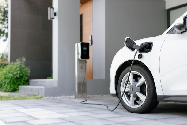 Concetto progressivo di auto elettrica e stazione di ricarica domestica in zona residenziale