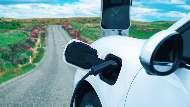 Concetto progressivo di auto elettrica presso la stazione di ricarica sulla strada collinare