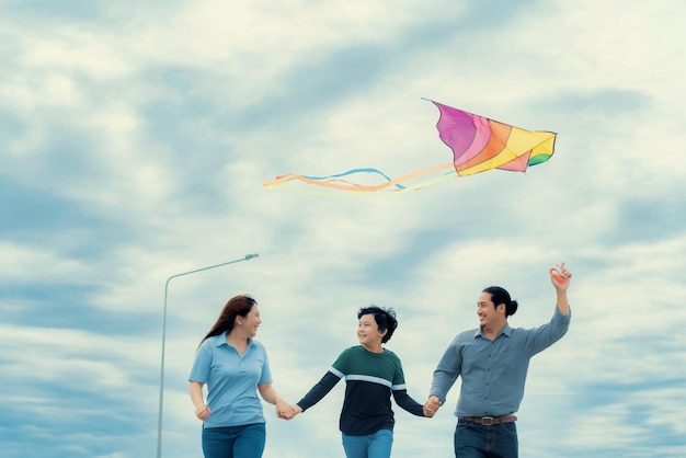 Concetto progressivo di vacanza in famiglia felice con aquilone volante all'aperto sulla strada