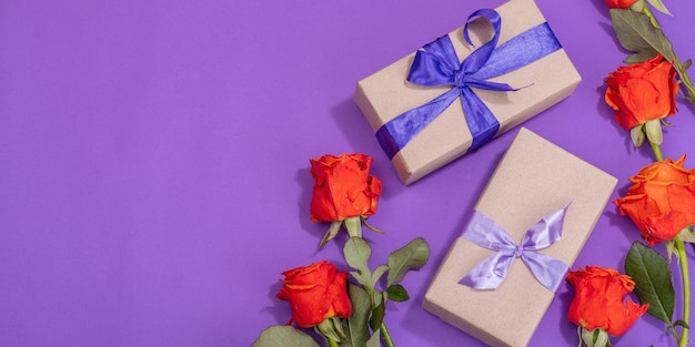 Concetto regalo zero rifiuti Rose luminose avvolte in una scatola a sorpresa di carta artigianale per l'anniversario della mamma o il giorno di San Valentino Biglietto di auguri di buon compleanno sfondo viola formato banner