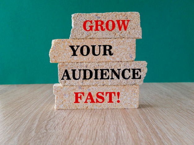 Concetto rosso parole Grow Your Audience Fast su blocchi di mattoni Bellissimo tavolo in legno