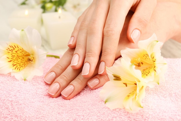 Concetto Spa Donna mani con bella manicure e fiori su asciugamano da vicino