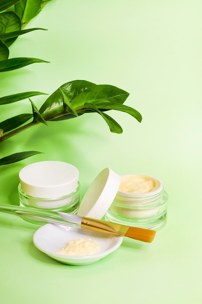 Concetto verticale di bellezza. cosmetici naturali di lusso, crema, maschera per la cura della pelle. accessori per estetista sul muro verde, copia spazio