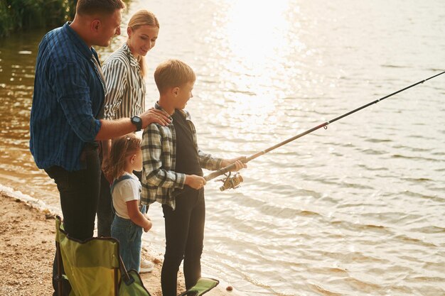 Concezione della vacanza Padre e madre con figlio e figlia sulla pesca insieme all'aperto in estate