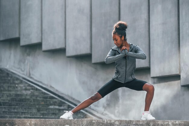 Concezione dello sport La giovane donna afroamericana in abiti sportivi si allena all'aperto durante il giorno