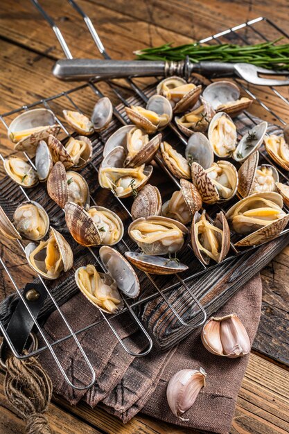 Conchiglie cotte vongole vongole su una griglia con aglio e rosmarino Sfondo in legno Vista dall'alto