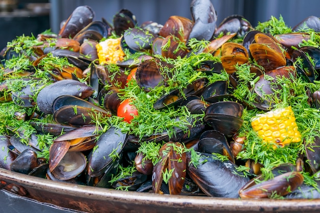 Conchiglie di cozze cotte con mais grigliato, pomodori ed erbe