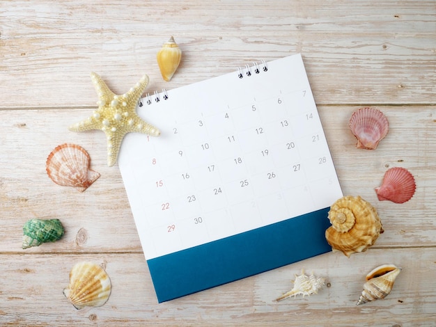 Conchiglie di mare e calendario su sfondo di legno