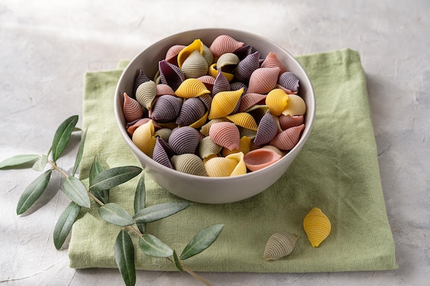 Conchiglie di pasta italiana colorata o conchiglie in una ciotola sul tovagliolo verde