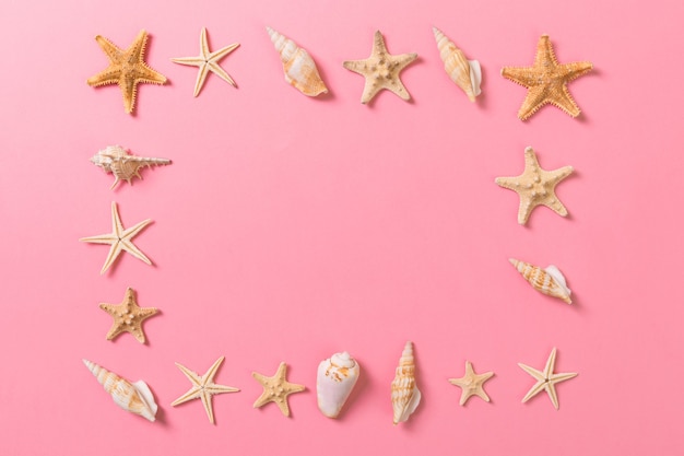 Conchiglie e stelle marine su sfondo rosa e sabbia. Concetto di tempo di vacanza.