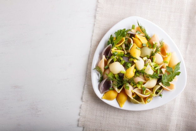 Conchiglie pasta colorata con frutta fresca su una tovaglia di lino