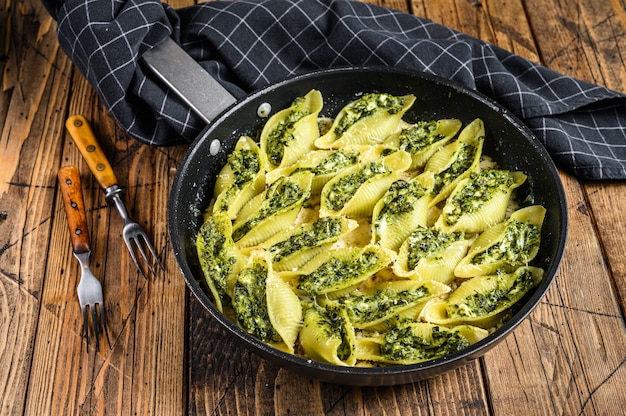 Conchiglioni di pasta ripieni di spinaci e formaggio cotti al sugo in padella