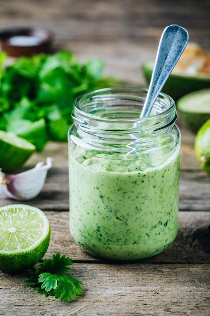 Condimento per insalata verde con avocado lime e coriandolo in un barattolo di vetro su fondo rustico