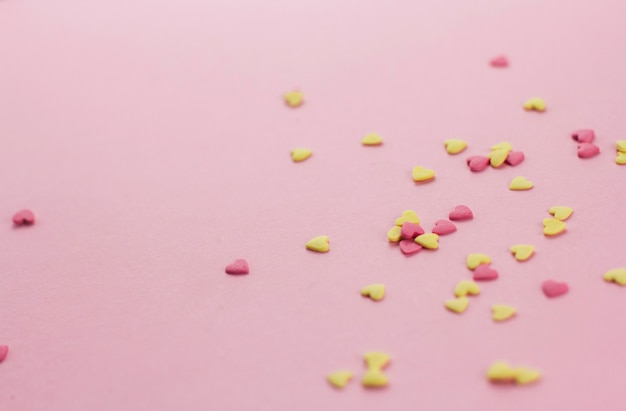confetti a forma di cuore giallo e rosa su uno sfondo rosa copia spazio.