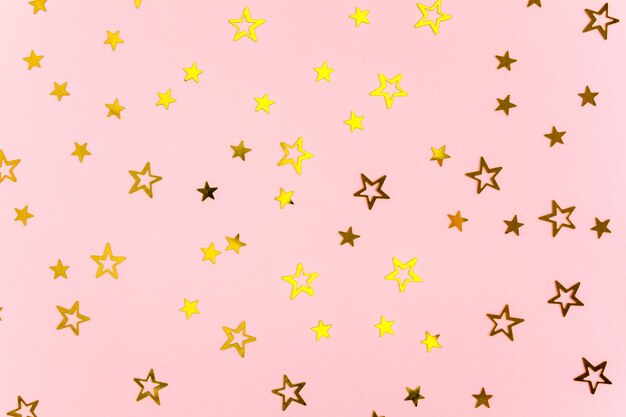Confetti stelle dorate su sfondo rosa sfondo festivo celebrazione colorata compleanno Natale o Capodanno modello vista superiore piatta