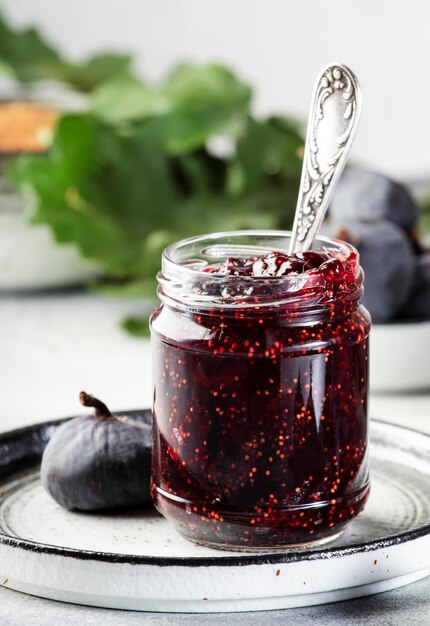 Confettura di fico in barattolo di vetro Frutta fresca sullo spazio negativo del tavolo da cucina grigio