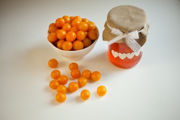 Confettura di susine gialle, frutti di bosco freschi. barattolo di vetro di marmellata fatta in casa su sfondo bianco