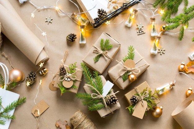 Confeziona un regalo per Natale e Capodanno in materiali ecologici: carta kraft, rami di abete vivo, pigne, spago. Etichette con mock up, decoro naturale, fatte a mano, fai da te. Atmosfera festosa. Sfondo di Natale