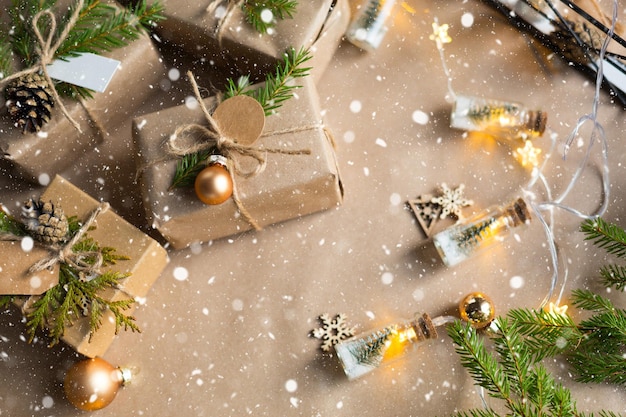 Confeziona un regalo per Natale e Capodanno in materiali ecologici: carta kraft, rami di abete vivo, pigne, spago, neve. Etichette con mock up, decoro naturale, fatte a mano, fai da te. Atmosfera festosa. Piatto, sfondo