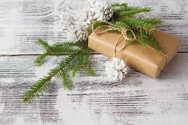 Confezionamento di pacchetti natalizi eco con carta marrone, spago e rami naturali ed elementi decorativi sul tavolo di legno