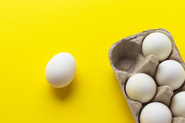 Confezione di uova di gallina fattoria in un contenitore di cartone su sfondo giallo. Cibo salutare. Vista piana laico e superiore con lo spazio della copia.