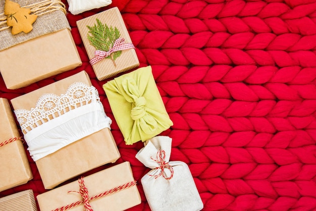 Confezione natalizia piatta a zero rifiuti, eco-compatibile. La composizione festiva di Natale confeziona regali in carta kraft su sfondo rosso, concetto di eco weekend invernale, eco decor