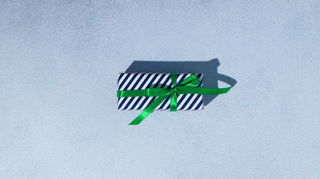 Confezione regalo a strisce blu e bianche con fiocchi verdi su sfondo grigio Spazio copia Mockup Posa piatta