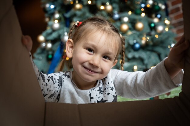 Confezione regalo aperta bambina con gioia e felicità. albero di Natale