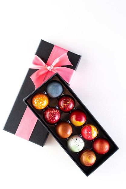 Confezione regalo aperta con assortimento di cioccolatini fatti in casa Caramelle al cioccolato dipinte a mano moderne Concetto di prodotto per cioccolatiere