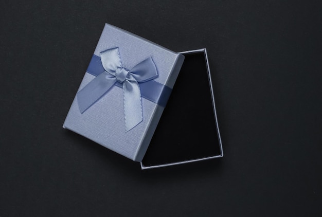 Confezione regalo aperta con fiocco su sfondo nero Composizione per natale compleanno o matrimonio Vista dall'alto
