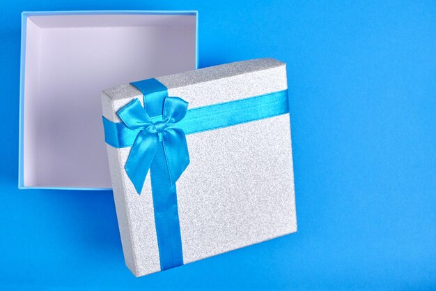 Confezione regalo aperta con nastro azzurro e fiocco su sfondo blu