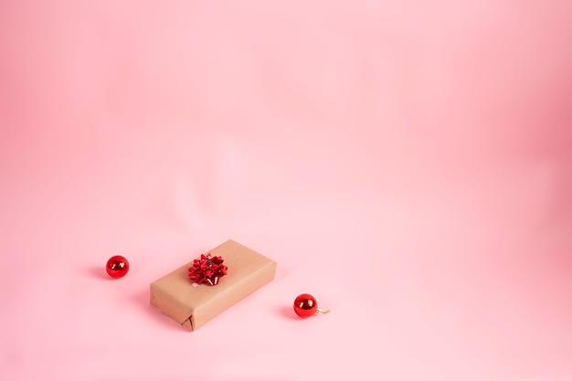 confezione regalo avvolta in carta kraft e fiocco rosso su sfondo rosa Natale concept