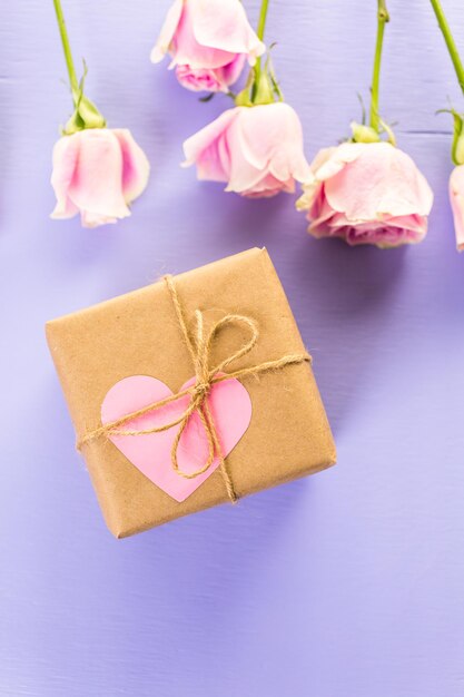 Confezione regalo avvolta in carta riciclata e decorata con cuore rosa con roselline rosa.