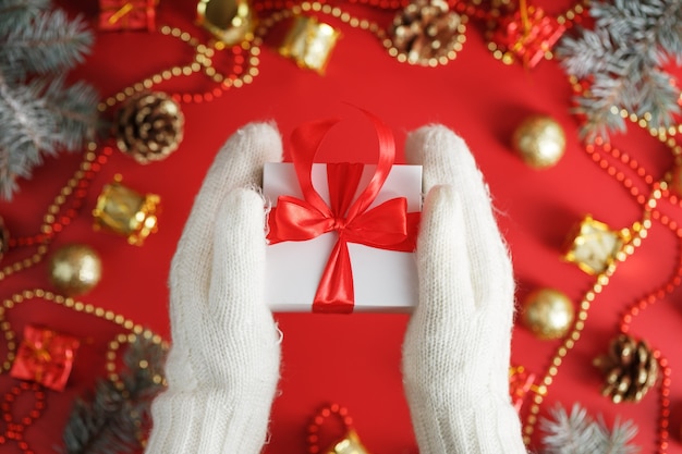 Confezione regalo bianca con fiocco rosso nei guanti