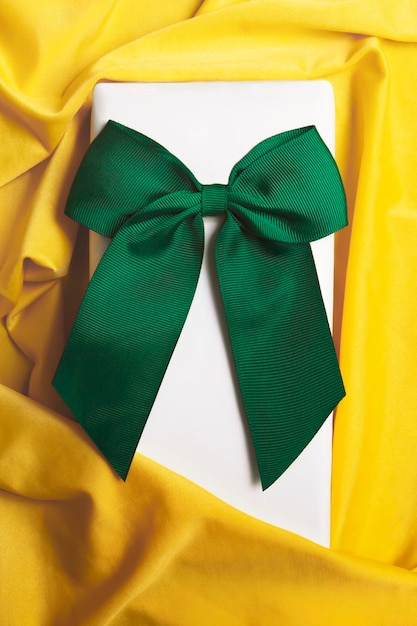 Confezione regalo bianca con grande fiocco verde e stoffa gialla