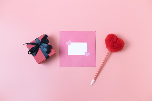 Confezione regalo busta e penna a cuore su sfondo rosa