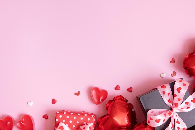 Confezione regalo candele e palloncini a forma di cuore rosso su sfondo rosa San Valentino sfondo romantico con spazio di copia