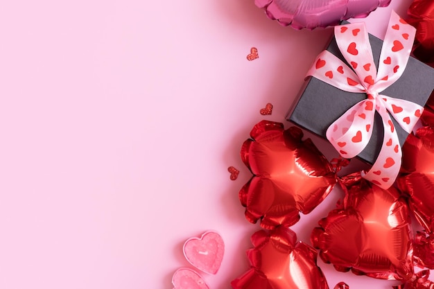 Confezione regalo candele e palloncini a forma di cuore rosso su sfondo rosa Sfondo di San Valentino con spazio di copia