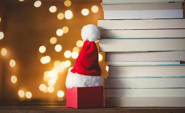 confezione regalo, cappello di Babbo Natale e pila di libri