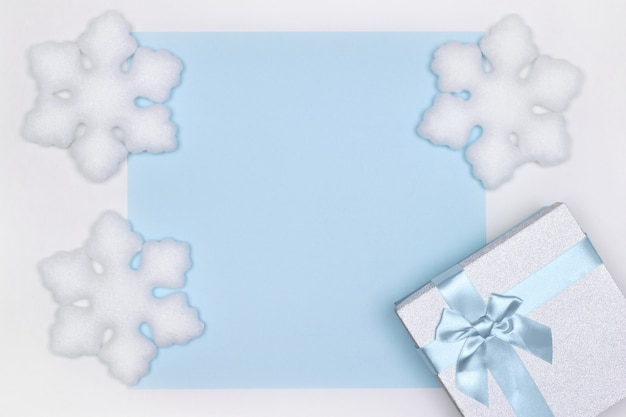 Confezione regalo con decorazioni di fiocchi di neve bianchi. Copia spazio. Vacanze invernali sfondo blu