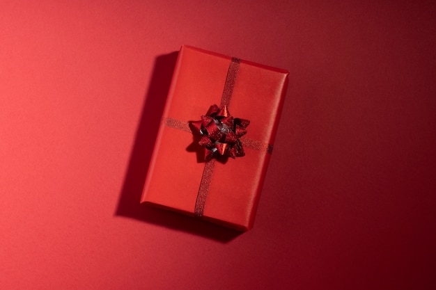 Confezione regalo con lunga ombra sulla superficie rossa. San Valentino, Natale, concetto di vacanza. Vista dall'alto, piatto
