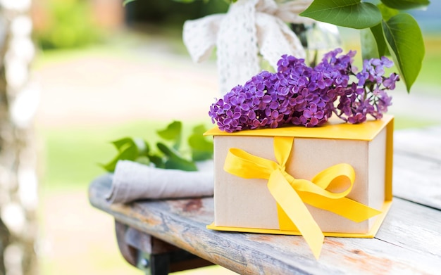 Confezione regalo con nastro giallo e mazzi di fiori lilla Un biglietto di auguri